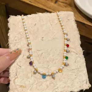 Close-up of pearl necklace with colorful glass charms on textured paper