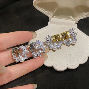 Macro view of butterfly and rhombic zirconia earrings with pearls on silver needles