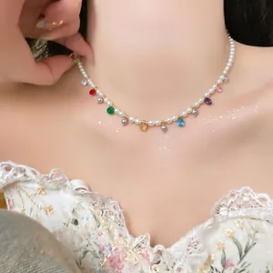 Detail view of a dainty pearl necklace with vibrant glass teardrop charms.