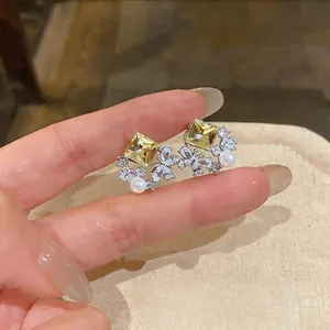 Macro detail of elegant butterfly stud earrings with yellow zircon and delicate pearl