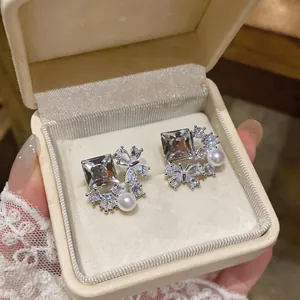 Close-up of elegant butterfly and zircon stud earrings with white pearls in a gift box