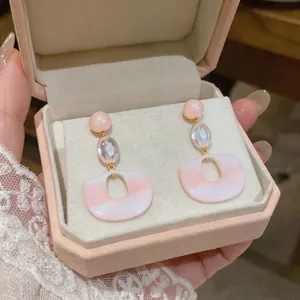 Detailed close-up of pink resin drop earrings presented in a luxury velvet jewelry box