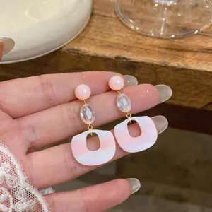 Close-up view of elegant pink resin dangle earrings featuring geometric cutout designs