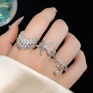 Detailed macro shot of elegant silver starfish and v-shaped sparkling rings on model fingers