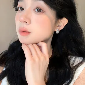 Model wearing delicate French style silver pearl earrings in a cluster design