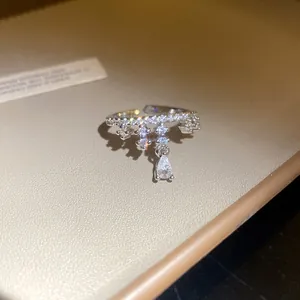 Close-up of a silver starfish open ring featuring a dangling pear-shaped sparkling stone