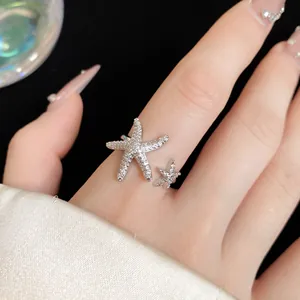 Detailed view of a sparkling starfish open ring with pavé stones on a manicured hand.