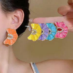 Close-up of vibrant pleated enamel flower earrings with sparkling rhinestone centers.