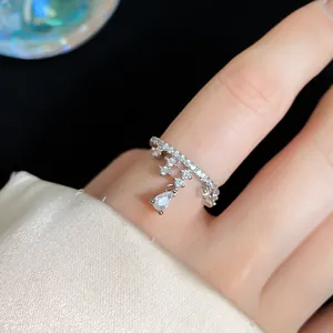 Close-up of a silver starfish open ring with a dangling pear-shaped zircon on a finger.