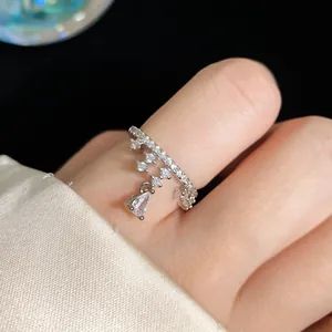 Close-up of a silver starfish open ring with a dangling pear-shaped crystal on a finger