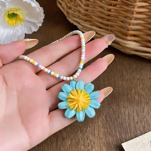 Primo piano di un ciondolo a margherita blu su una collana di perle colorate