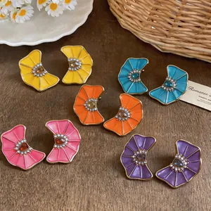 Detailed view of colorful pleated enamel flower stud earrings in multiple colors