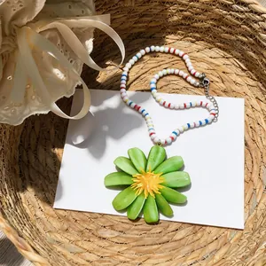 Dettaglio ravvicinato della collana estiva di perline con ciondolo a fiore verde