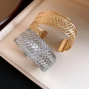 Detailed view of gold and silver woven metal mesh open cuff bracelets