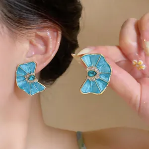 Detail shot of blue enamel fan-shaped earrings with rhinestones and teardrop crystal.