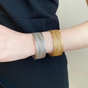 Close-up detail showing the intricate texture of gold and silver woven metal bangles on a wrist.