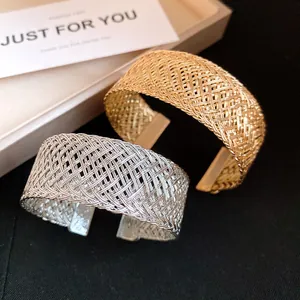 Close-up of gold and silver woven metal cuff bracelets with vintage braided texture