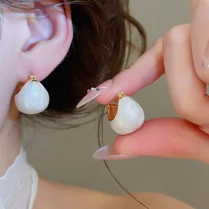 Close-up of vintage white drip oil bean hoop earrings with gold plating.