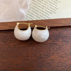 Detailed macro view of white enamel bean-shaped earrings with 18k gold plating.