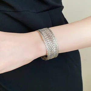 Detailed view of a minimalist silver woven metal cuff bracelet worn on a female wrist