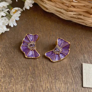 Detailed view of elegant purple enamel flower stud earrings with sparkling crystals.
