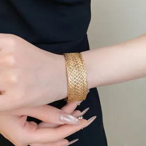 Close-up of a vintage golden metallic woven open cuff bracelet on a woman's wrist