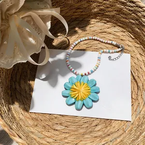 Primo piano di una collana di perline colorate con un grande ciondolo a margherita blu e giallo