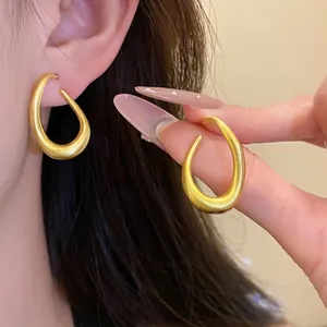 Elegante minimalistische gedrehte ovale Creolen mit strukturierter matter Goldoberfläche.