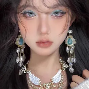 Close-up of elegant blue shell and flower drop earrings with matching wing necklace