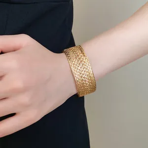 Macro view showing the intricate texture of a gold woven mesh cuff bracelet on wrist