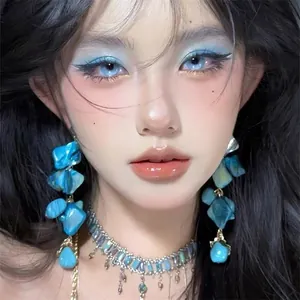Close-up of artistic blue shell earrings and matching necklace on a model for summer.