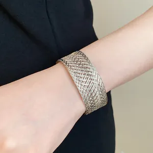 Detailed macro shot of a wide silver-toned metal woven mesh cuff bracelet on female wrist