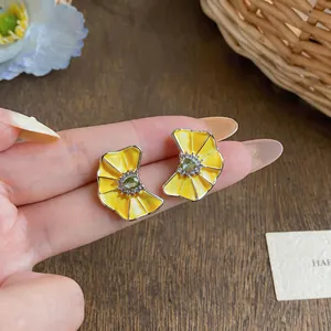 Detailed view of yellow enamel flower earrings with crystal center and silver needle.