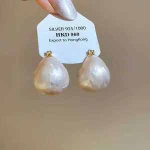 Close-up of elegant 18k gold-plated pearlescent drop earrings presented on card
