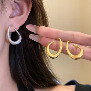Detailansicht matter gold- und silberfarbener gedrehter ovaler Creolen am Model.