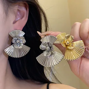Detail of retro fan-shaped flower earrings with pleated metal texture in gold and silver.