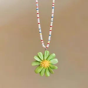 Dettaglio di un ciondolo a margherita verde su una collana di perline colorate