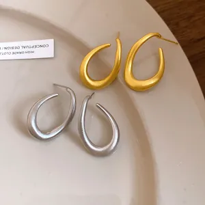 Detailansicht von eleganten matten Tropfenohrringen in Gold und Silber auf einem Teller