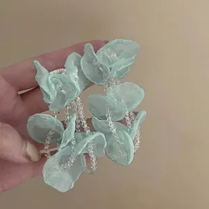 Detailed close-up view of seafoam green fabric flower drop earrings with clear beads