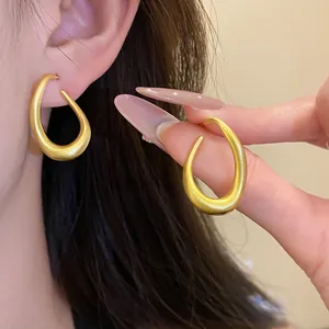 Detailansicht der minimalistischen mattgoldenen ovalen Ohrringe am Ohr getragen