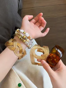 Detailed view of vintage amber resin bangle and gold woven mesh bracelet on a wrist