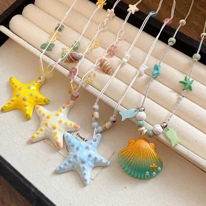 Primer plano de dijes de estrellas de mar y caracolas en collares de perlas de playa