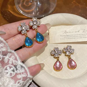 Dettaglio di orecchini vintage in stile palazzo con fiori e ciondoli a goccia d'acqua.