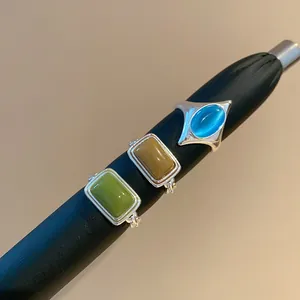 Nahaufnahme von geometrischen Vintage-Katzenaugenringen in Grün, Ocker und Blau