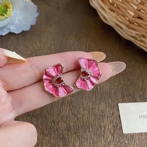 Detailed macro view of pink enamel pleated flower stud earrings featuring a red heart gemstone