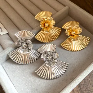 Macro detail of vintage fan-shaped earrings with metallic flower and pleated texture.