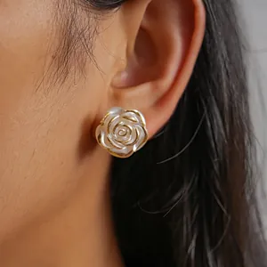 Detailed view of vintage white camellia rose stud earring with gold-tone trim on ear