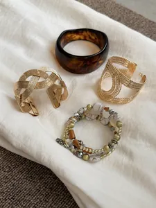 Detailed macro view of vintage Maillard resin bangle and textured gold cuff bracelet set.