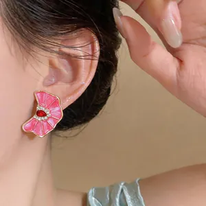 Close-up of pink enamel flower stud earring with red gemstone and rhinestones