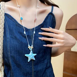 Primer plano de un collar con colgante de estrella de mar azul en un vestido denim